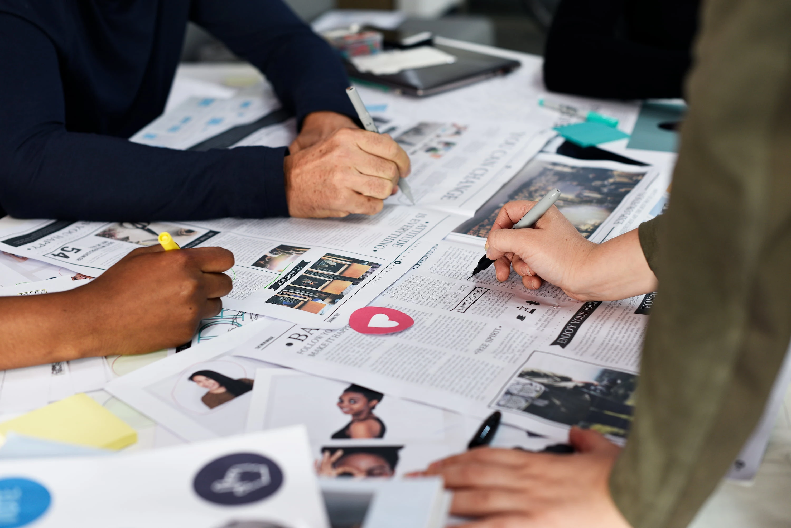 Hands annotating printed campaign materials and a mood board with markers and sticky notes