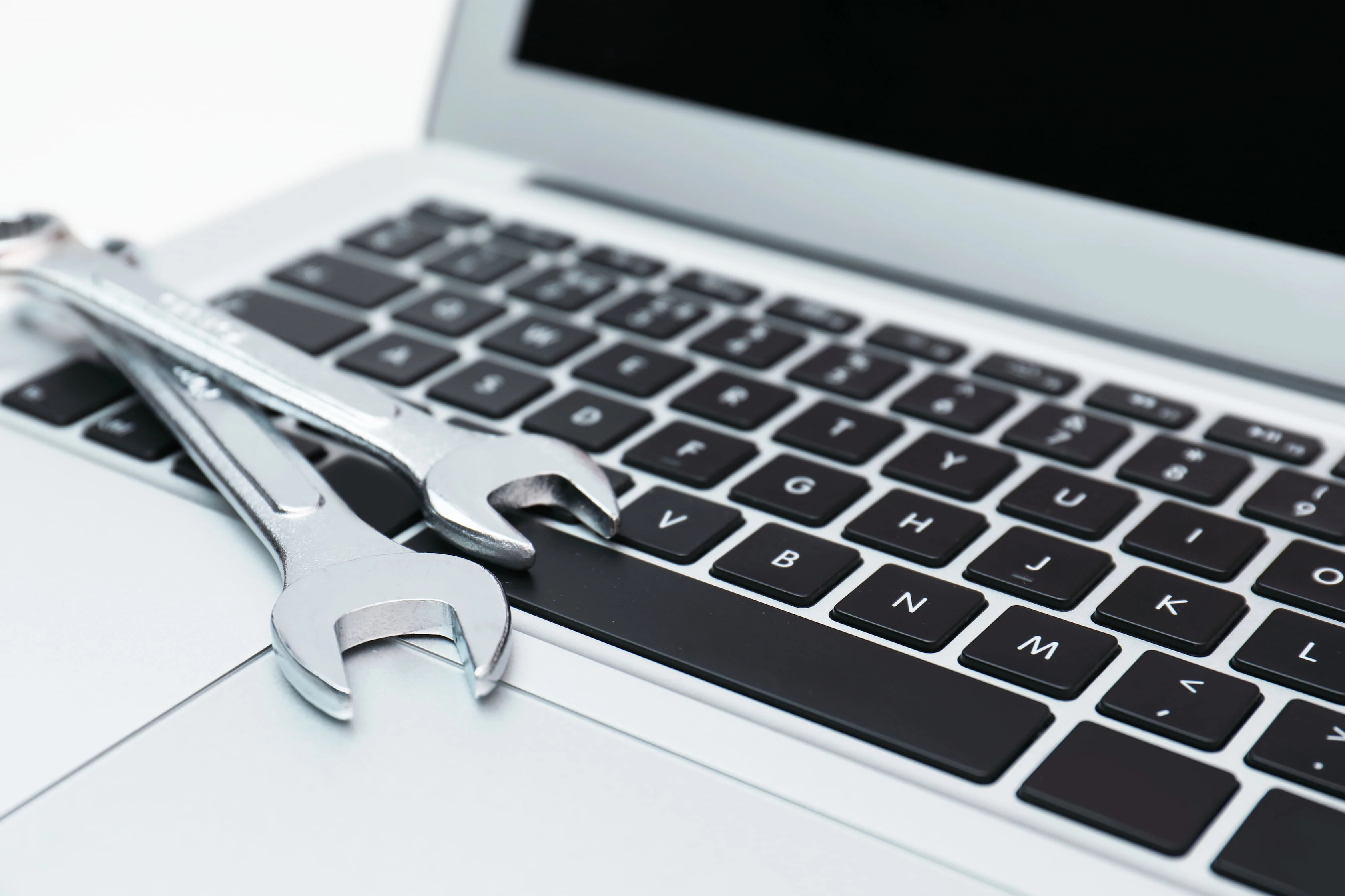 Two wrenches resting on a laptop keyboard